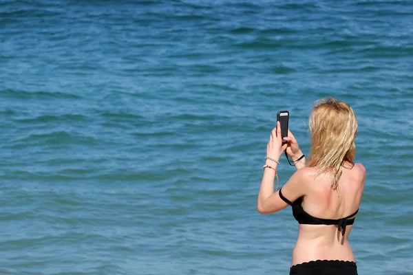 Blonde tourist girl in bikini relaxed and take photos by a mobil — Stock Photo, Image