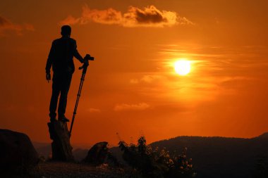 Fotoğrafçı, gün batımında dağda fotoğraf çekiyor.