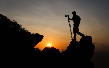 Fotoğrafçı Tayland 'da gün batımında fotoğraf çekmek için dağın tepesine tırmanıyor..