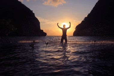 Sabaha karşı sahilde deniz suyuyla oynayan adamların silueti..