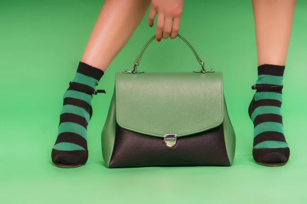 緑の背景に緑と黒のハンドバッグ — ストック写真