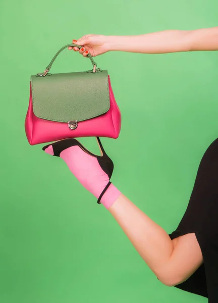 Mulher em uma saia segurando bolsa verde e rosa em uma perna — Fotografia de Stock