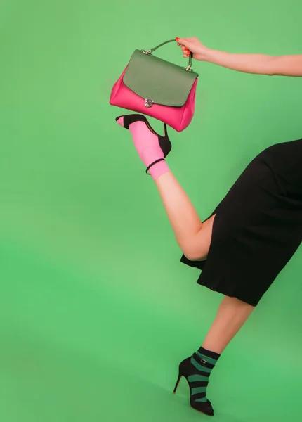 Женщина в черной юбке с розовой и зеленой женской сумочкой — стоковое фото