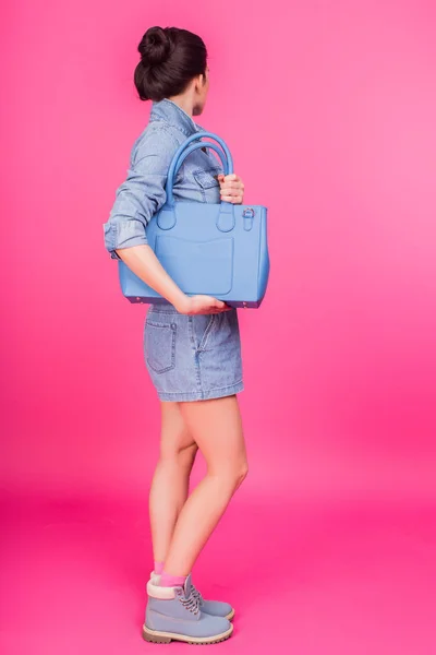 Mujer de pie con bolso azul sobre fondo rosa — Foto de Stock