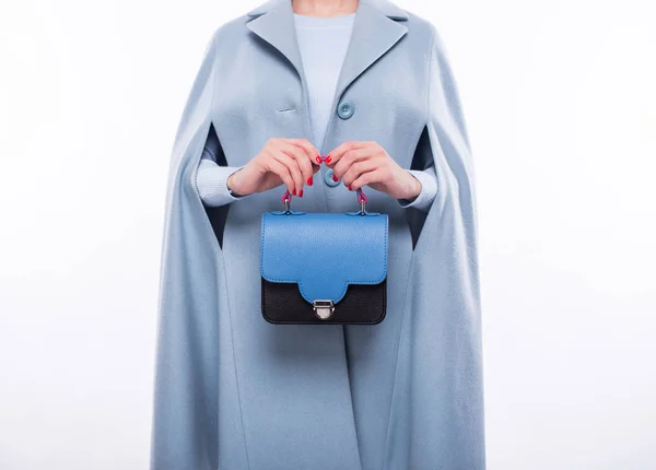 Wanita muda dalam mantel memegang tas biru-hitam — Stok Foto