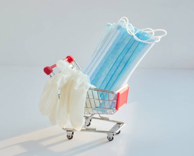 Tıbbi maske ve eldivenli alışveriş arabası. Coronavirus önleme ve koruyucu maske ve eldiven konsepti satın alma.