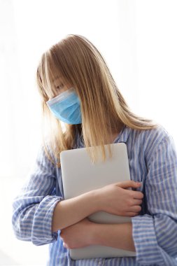 İzolasyon sırasında mesafesini koruyor. Maskeli ve gecelikli kadın Coronavirus covid-19 karantinası sırasında evde dizüstü bilgisayarla çalışıyor veya serbest çalışıyor.