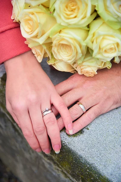 Bride and groom hands with rings and flowers Stock Photo