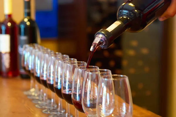 Bir düzine şarap bardakları ve dökücü ile kırmızı şarap şişesi