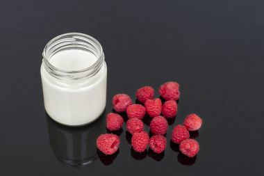 Yoğurt cam kavanoz ve ahududu siyah bir arka plan - yatay