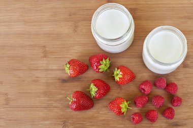 Cam Kavanoz, ahududu ve çilek - üstten ahşap bir zemin üzerine yoğurt