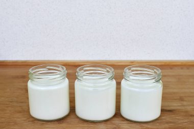 Ahşap arka plan - yatay üzerinde Yoğurtlu üç Cam Kavanoz