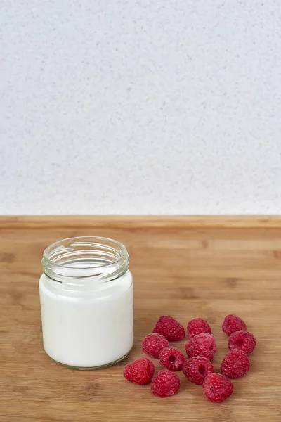 Yogurt dalam botol kaca dan raspberry pada latar belakang kayu vertikal — Stok Foto
