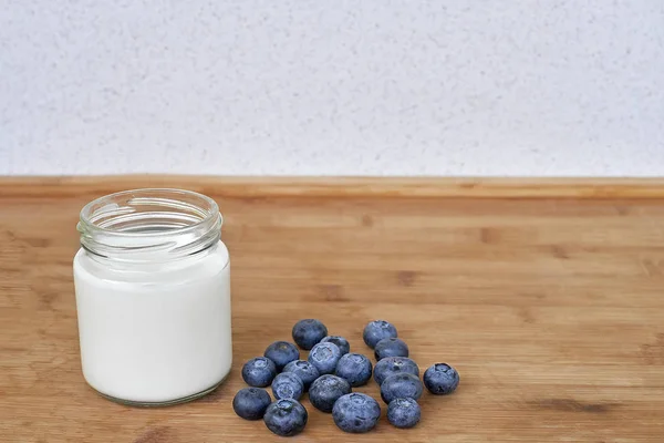 Jogurt do sklenice a borůvky na dřevěné pozadí - horizontální — Stock fotografie