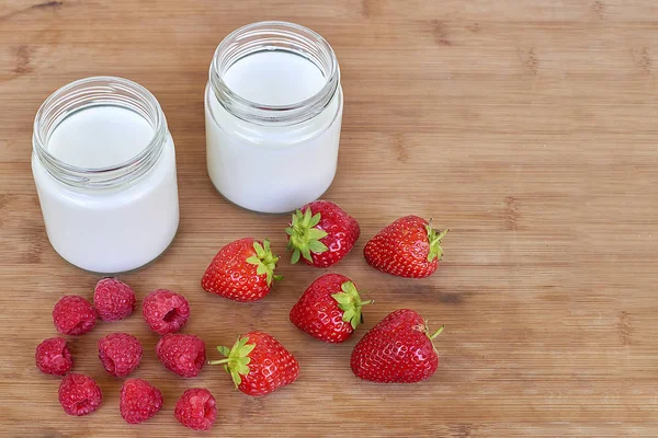 Jogurt v sklenice, maliny a jahody na dřevěné pozadí - vzorovou šablonu — Stock fotografie