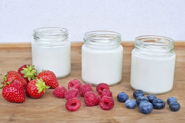 Trzy szklane słoiki z jogurtem i odmiana jagody — Zdjęcie stockowe