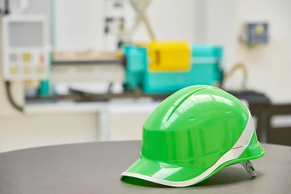 Green safety helmet on industrial background