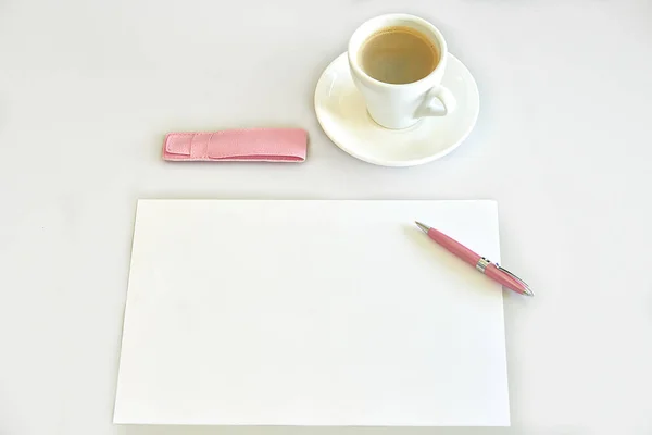 Café expreso, hoja de papel, bolígrafo rosa y estuche de bolígrafo en un escritorio Imagen De Stock