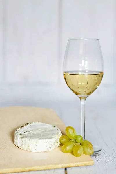 Copo de vinho branco, queijo camembert e uva branca sobre fundo de madeira — Fotografia de Stock