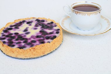 Fincan çay ve yaban mersinli pasta beyaz bir arka planda - yatay