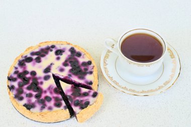 Fincan çay ve yaban mersinli pasta beyaz bir arka planda - yüksek açılı görünüş