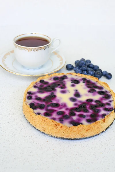 Fincan çay ve yaban mersinli pasta beyaz bir arka planda - dikey