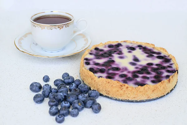 Fincan çay, kek, krepteki ve beyaz bir arka plan üzerinde yaban mersini