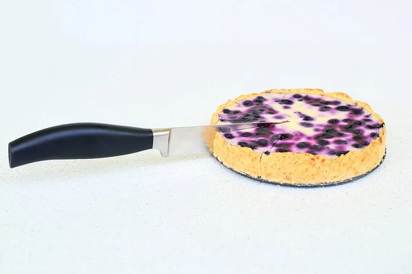 Cuchillo que corta el pastel de arándanos sobre un fondo blanco — Foto de Stock
