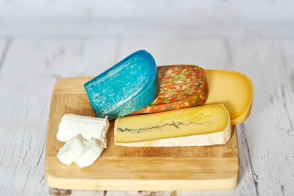 Queijo de cabra, queijo de lavanda, queijo azul, queijo picante e queijo emmental em uma tábua de madeira — Fotografia de Stock