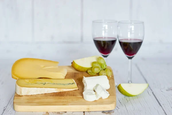 Dois copos de vinho tinto, pêra e placa de queijo em bandeja de madeira — Fotografia de Stock