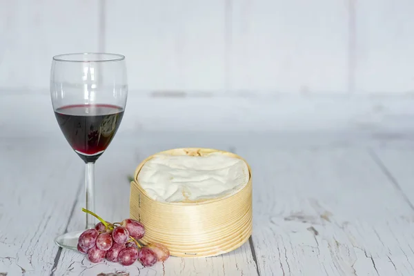 Copo de vinho tinto, uvas vermelhas e queijo camembert em caixa de madeira - horizontal — Fotografia de Stock