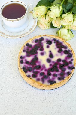 Böğürtlenli turta, fincan çay ve beyaz güller beyaz bir arka planda - dikey