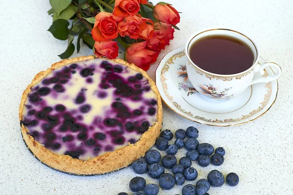 Böğürtlenli turta, fincan çay, yığın, yaban mersini ve kırmızı gül beyaz bir arka planda - yüksek açılı görünüş