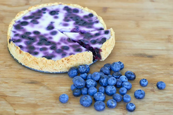 Blueberry baked pie and heap of blueberries on a wooden background — Stock Photo, Image