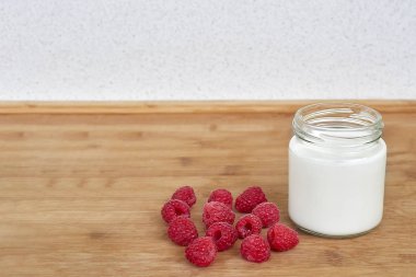 Cam kavanoza yoğurt ve ahududu ahşap zemin yatay