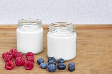 Yoğurt, ahududu ve yaban mersini yatay iki cam kavanoz