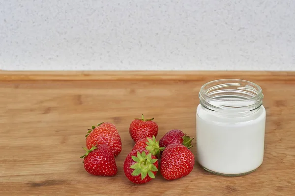 Skleněná dóza s jogurtem a sedm jahody na vodorovné dřevěné pozadí — Stock fotografie