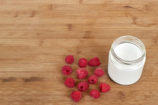 Botol kaca dengan yogurt dan raspberry pada tampilan sudut horisontal kayu — Stok Foto