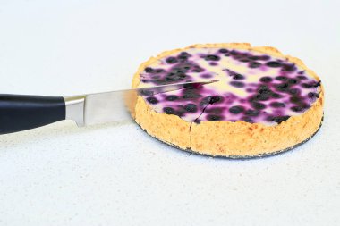 Böğürtlenli turta mutfak bıçağı tarafından beyaz bir arka plan üzerinde kesme - yakın çekim