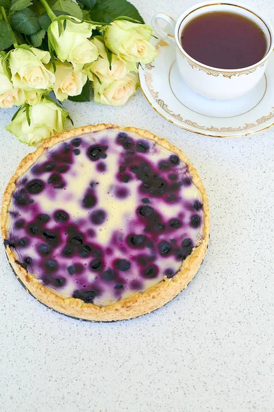 Böğürtlenli turta, fincan çay, yaban mersini ve kırmızı gül beyaz bir arka planda - natürmort yiyecek yığını