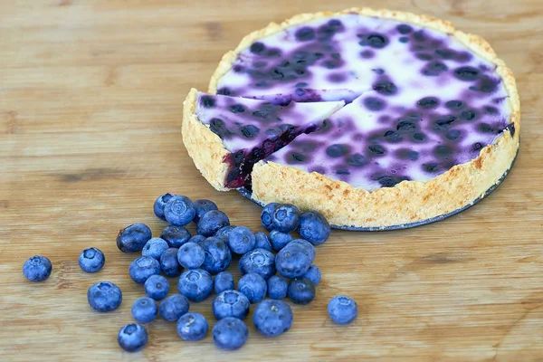 Blueberry pie and heap of blueberries on a wooden background - still life food — Stock Photo, Image