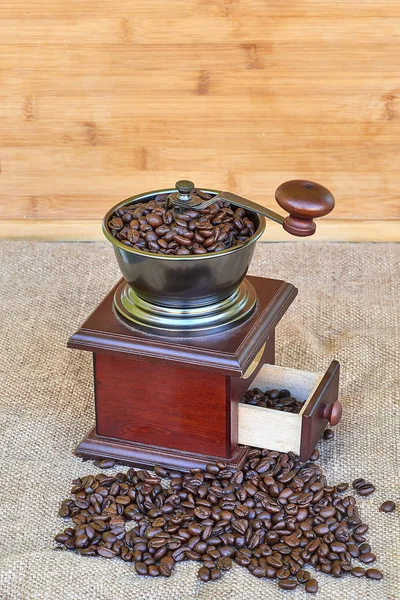 Kahve değirmeni kavrulmuş kahve çekirdekleri - ahşap arka plan tam