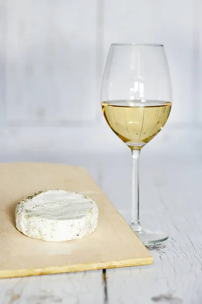 Copo de vinho branco e queijo camembert sobre um fundo de madeira — Fotografia de Stock