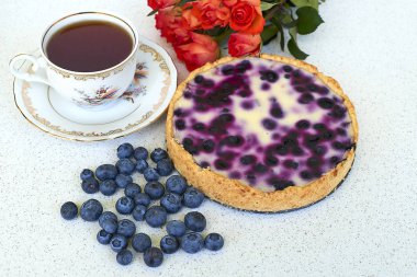 Böğürtlenli turta, fincan çay, yaban mersini ve kırmızı gül beyaz bir arka planda - natürmort yiyecek yığını 
