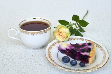 Böğürtlenli turta, fincan çay ve beyaz gül beyaz bir arka plan üzerinde