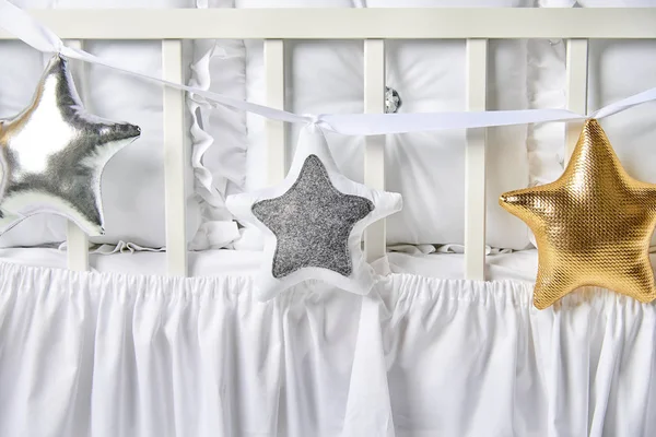 Ezüst, arany és fehér csillag alakú párnák egy fehér kiságy — Stock Fotó