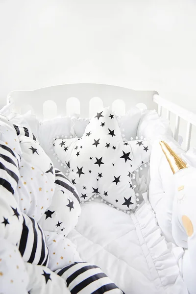 Gezellige babywieg met witte vierkante kussens en lappendeken Trooster deken met sterren en zwarte strepen — Stockfoto