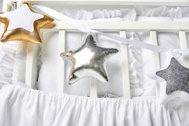 Gümüş, altın ve beyaz yıldız şekilli yastıklar üzerinde beyaz Bebek karyolası