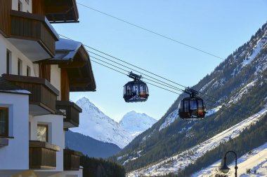 Ischgl, Austria - December 24, 2017: Modern aerial tramway in Austrian Alps ski resort. Highland cable car leads between hills from village to ski slope. Cable car station locates in Ischgl city center. View from the city. clipart