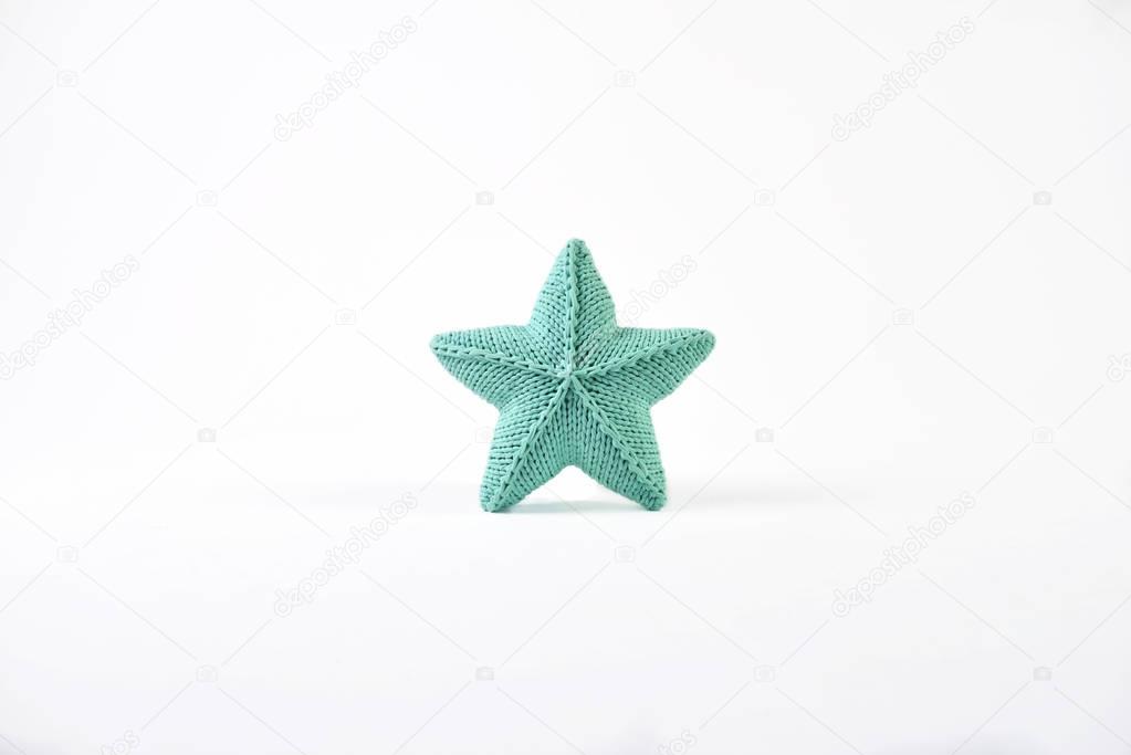 Blue-green knitted five-pointed star shaped pillow on white background